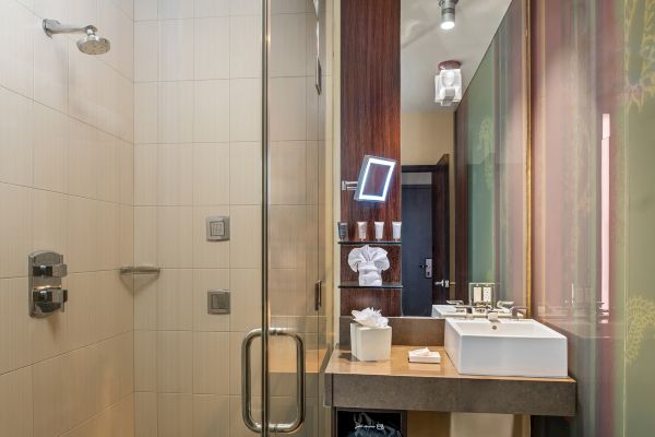 A modern bathroom features a glass-enclosed shower, a sink with a mirror, toiletries, and stylish lighting fixtures.